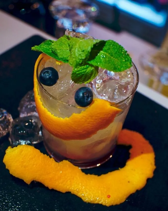 Cocktail con menta fresca, mirtilli e scorza d'arancia